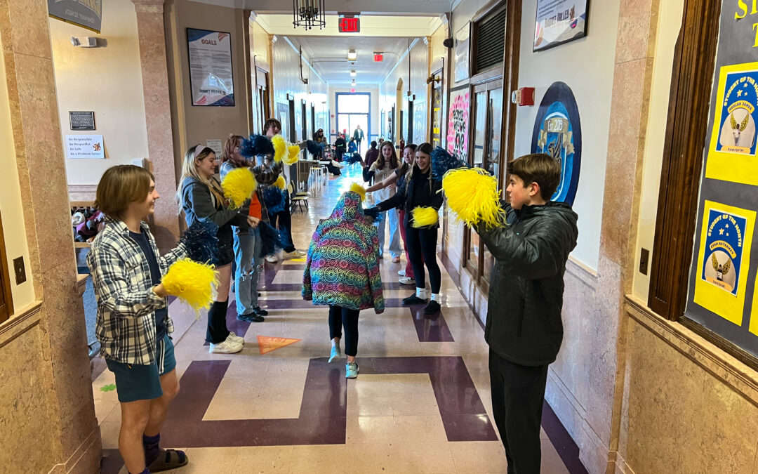 PSET members cheer on other students with pompoms.