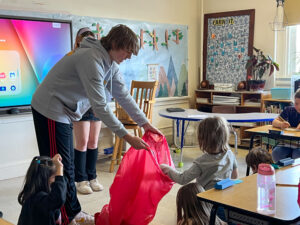 A PSET teen holds out a big red bag for an elementary student to throw negativity away into. 